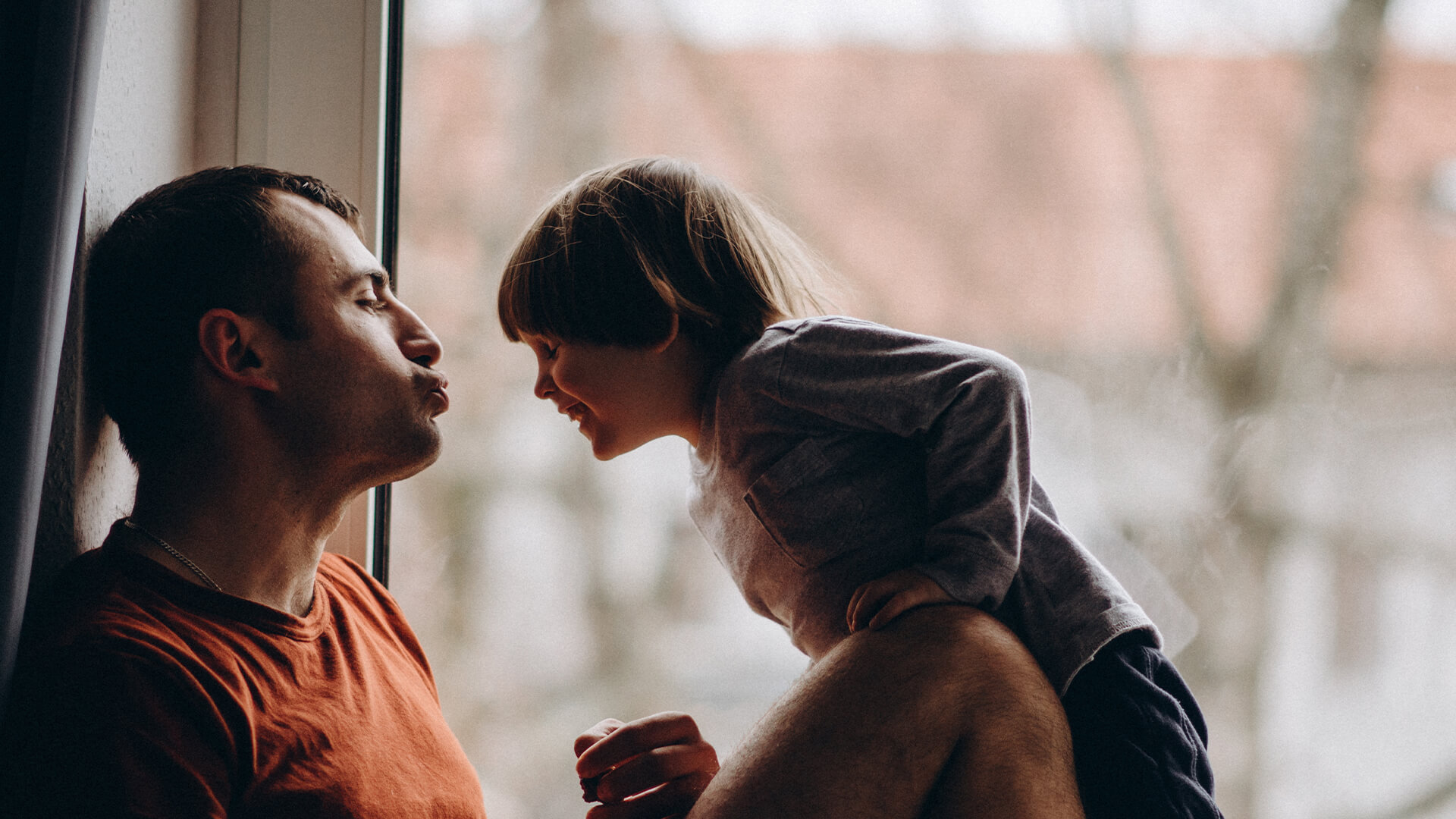 Father and young child sharing a playful moment by the window, symbolizing connection and care in child support matters — Resolve Divorce Adelaide family law.