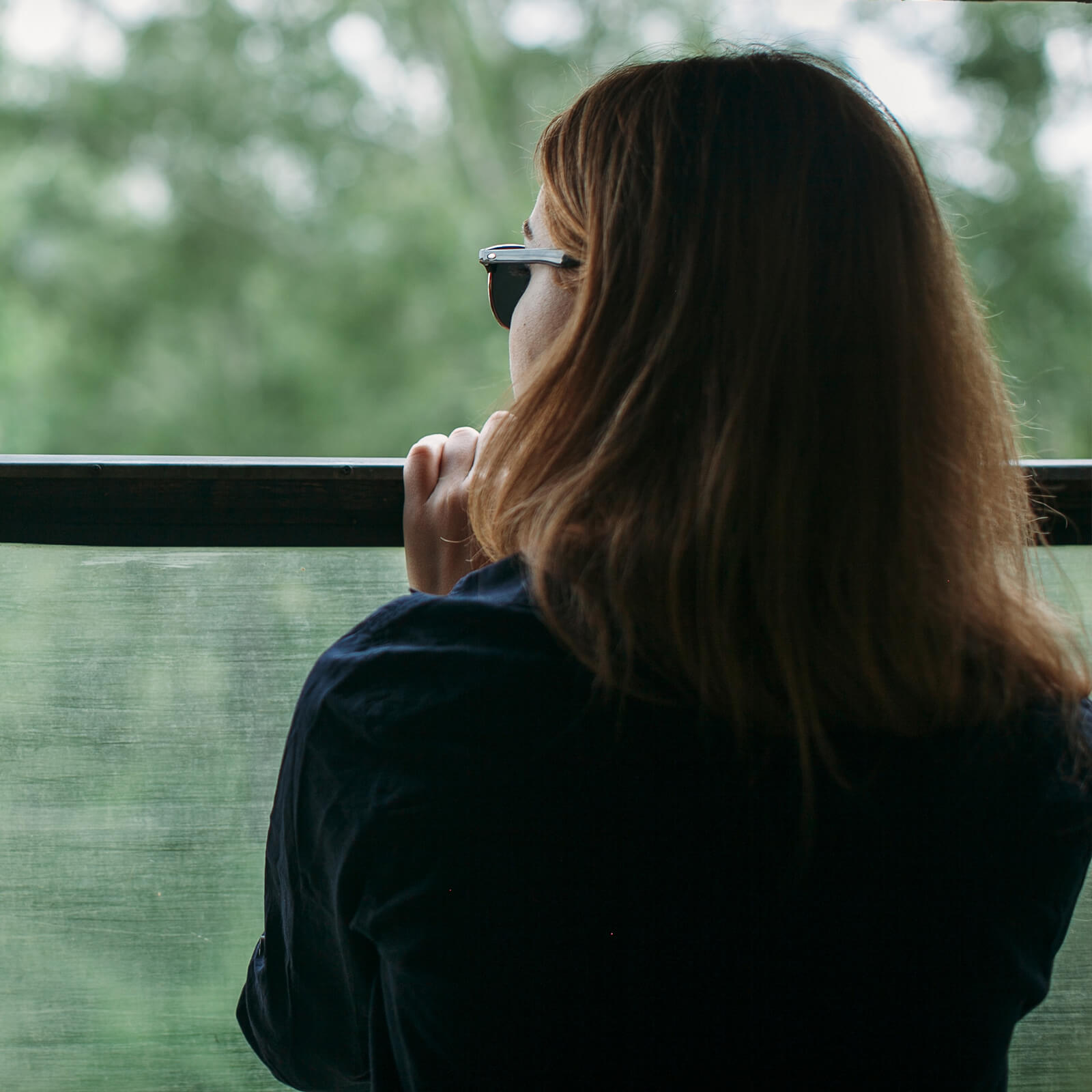 Woman looking out a window with trees in the background, symbolizing reflection and support during spousal maintenance discussions — Resolve Divorce Adelaide family law firm.