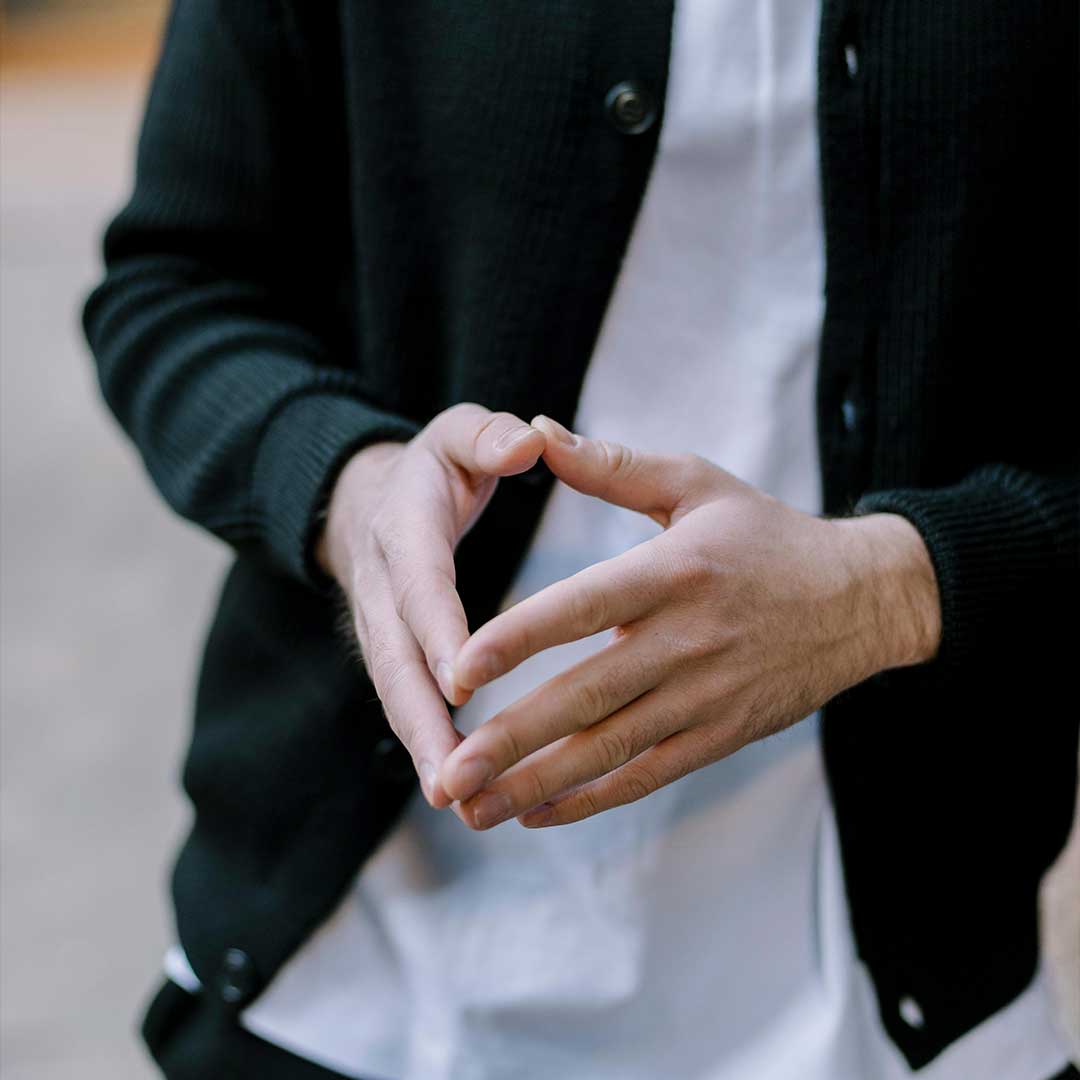 Resolve Divorce testimonial image showing a man’s hands forming a relaxed gesture, wearing a black cardigan over a white shirt.