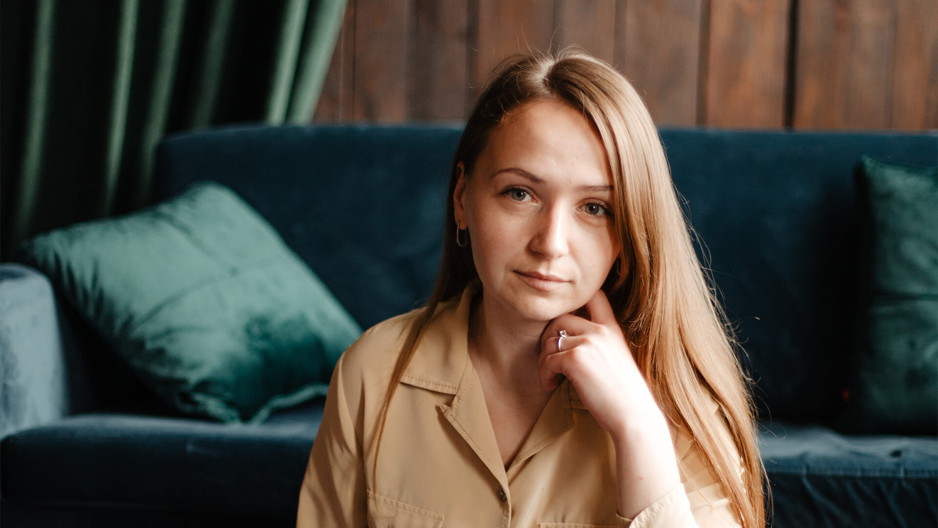 Woman sitting on a dark green couch with a thoughtful expression, symbolizing reflection and support during separation and divorce — Resolve Divorce Adelaide family law.