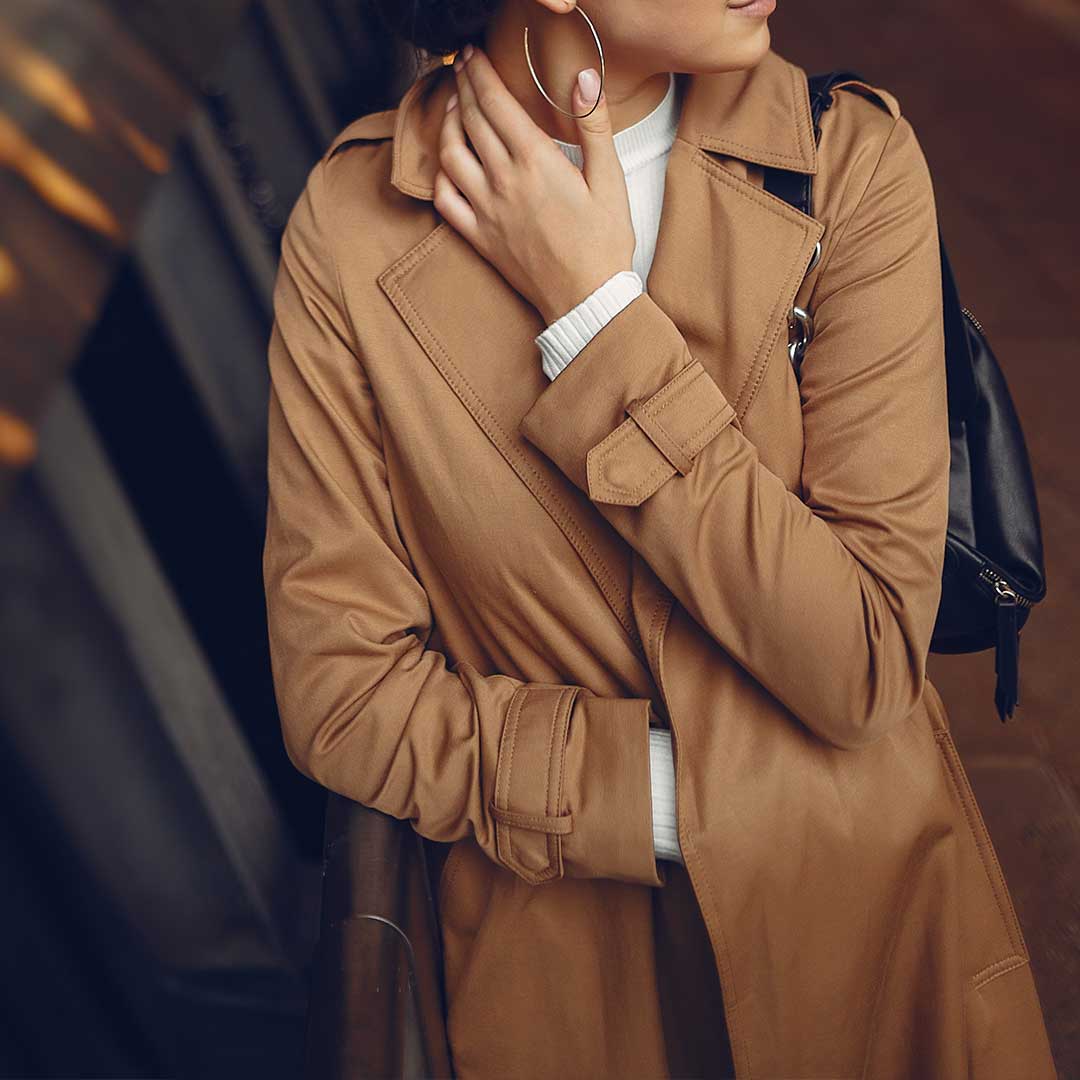 Resolve Divorce testimonial image showing a woman in a tan trench coat and white turtleneck, symbolising confidence and composure.